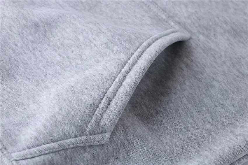 Men’s hooded sweatshirt in gray cotton fabric with stitched pocket opening, highlighting craftsmanship, comfort, and casual streetwear appeal.