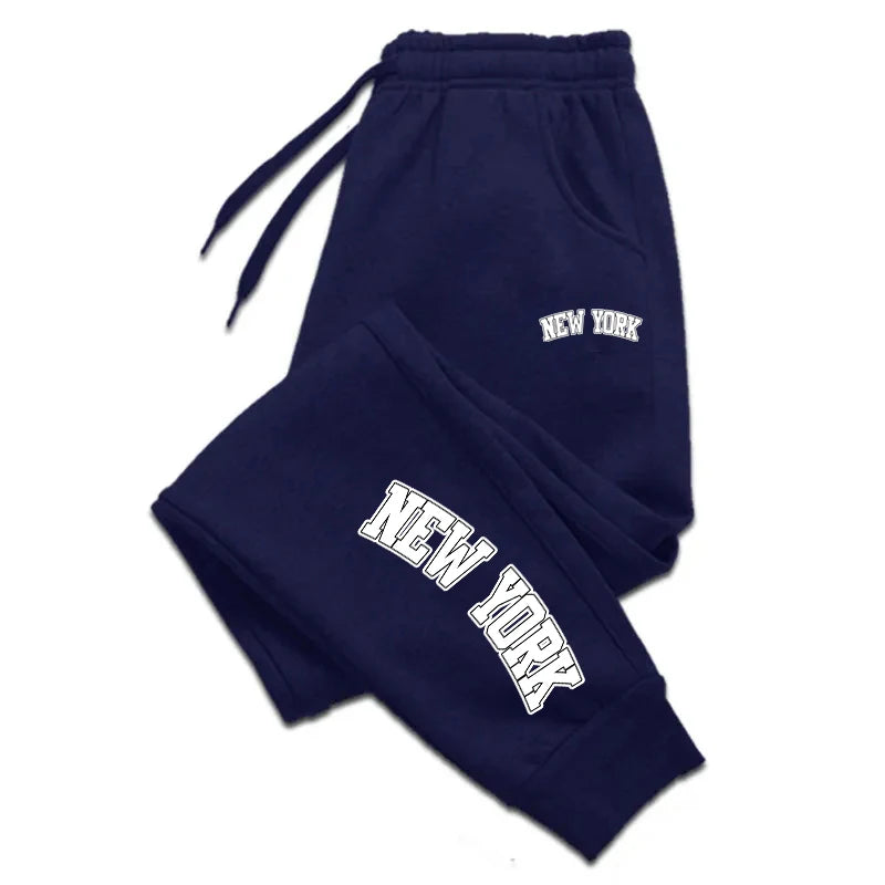 Men’s casual sweatpants in navy blue with bold white “NEW YORK” print, featuring drawstring waist for comfort and sporty style.